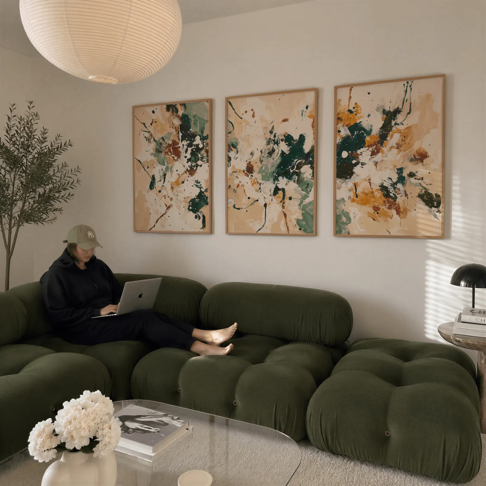 green and brown abstract wall art set of 3, above a plush olive velvet sectional beneath a paper lantern light