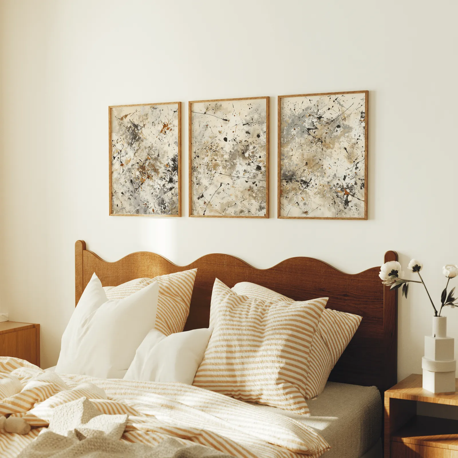 neutral abstract splatter wall art set of 3, above a scalloped wooden headboard with striped pillows