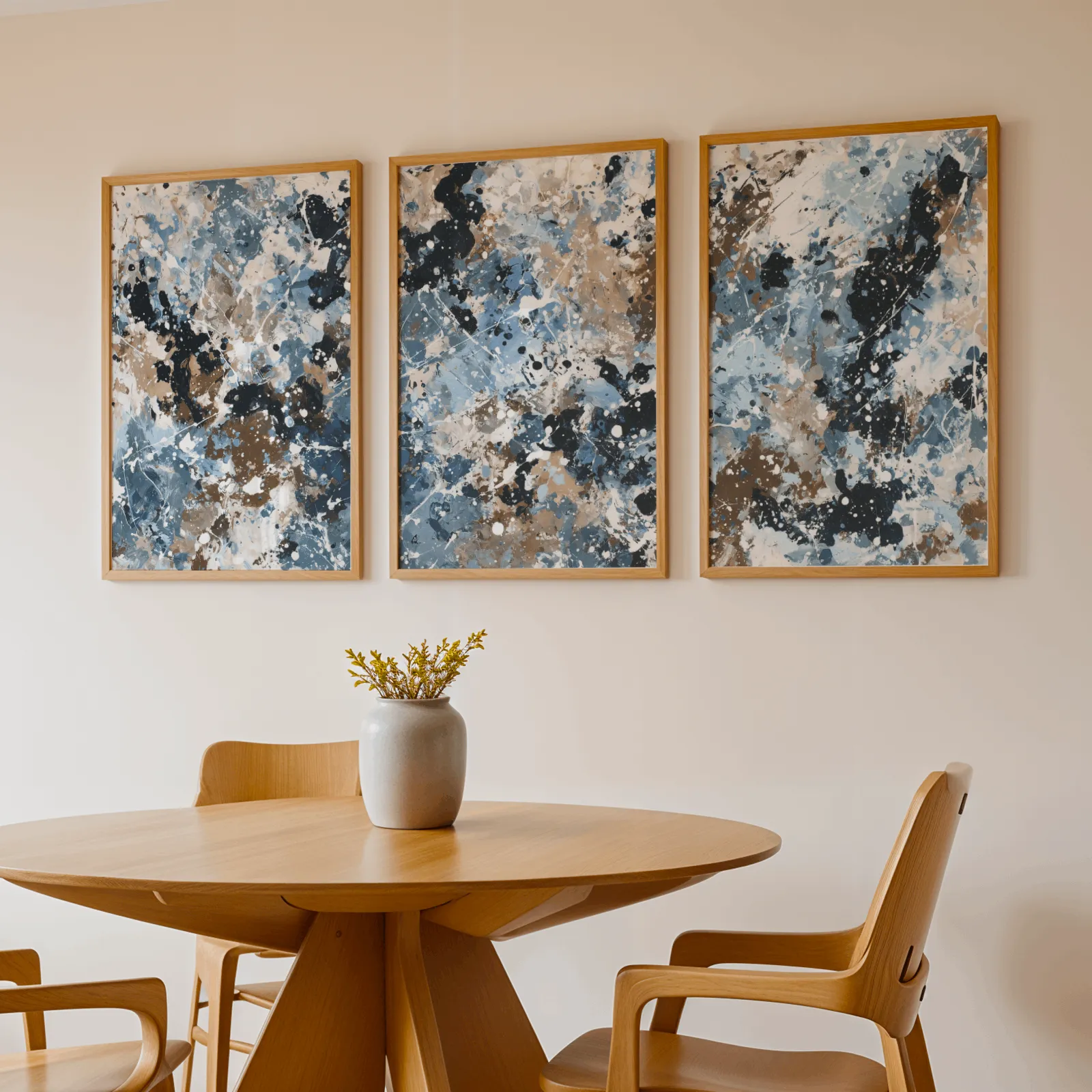 blue brown abstract splatter triptych wall art, above a round wooden table with a stoneware vase