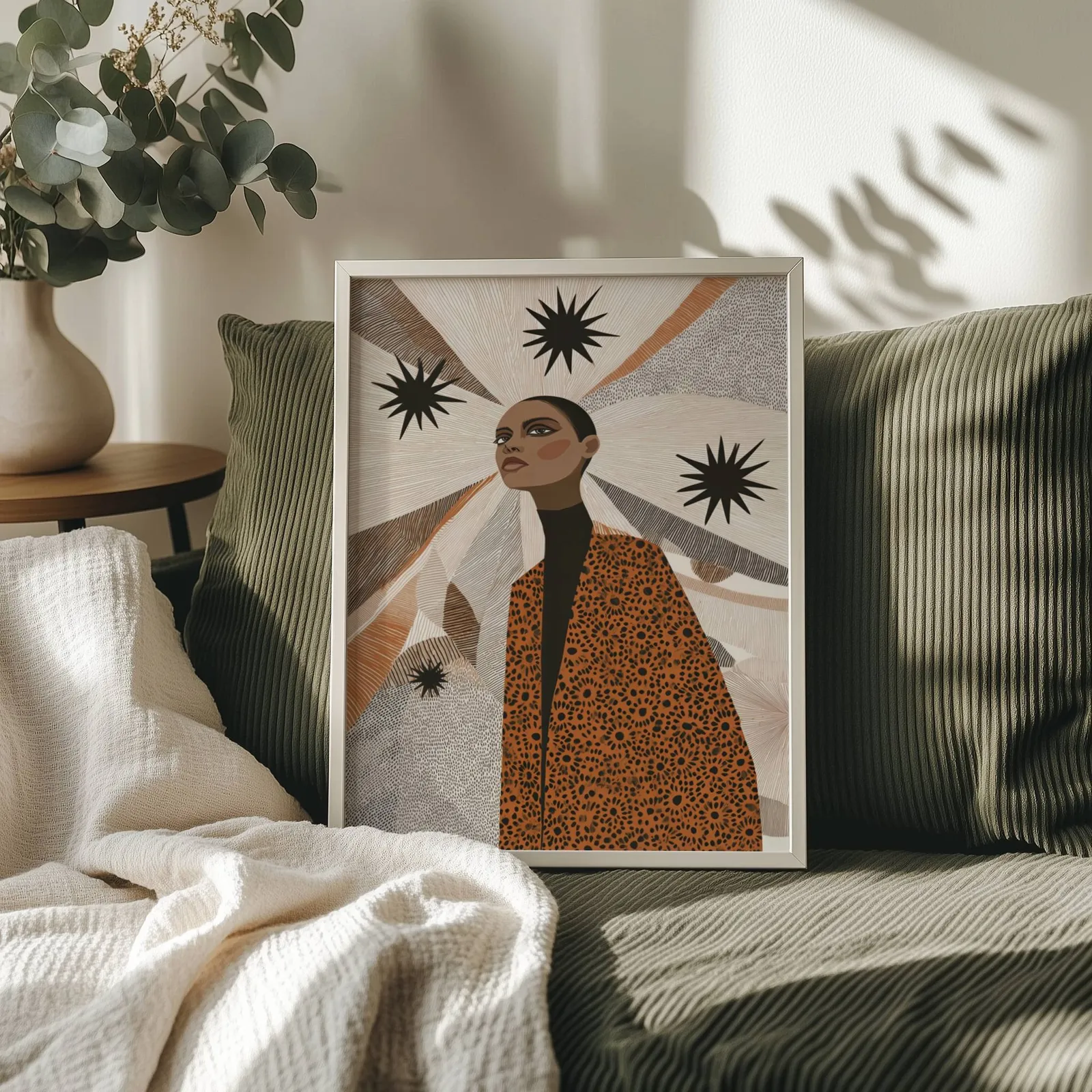 terracotta abstract woman wall art with stars, propped on an olive corduroy sofa beside a eucalyptus vase