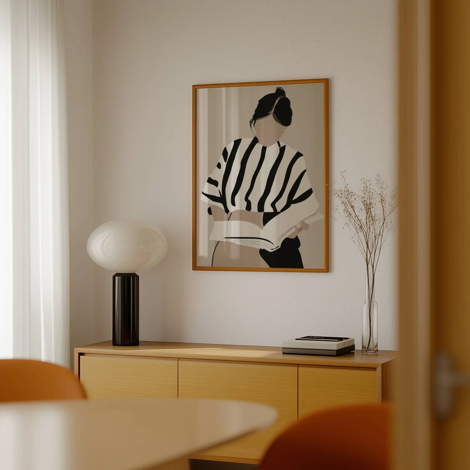 woman reading minimalist wall art, above a light wood sideboard beside a bulbous black lamp