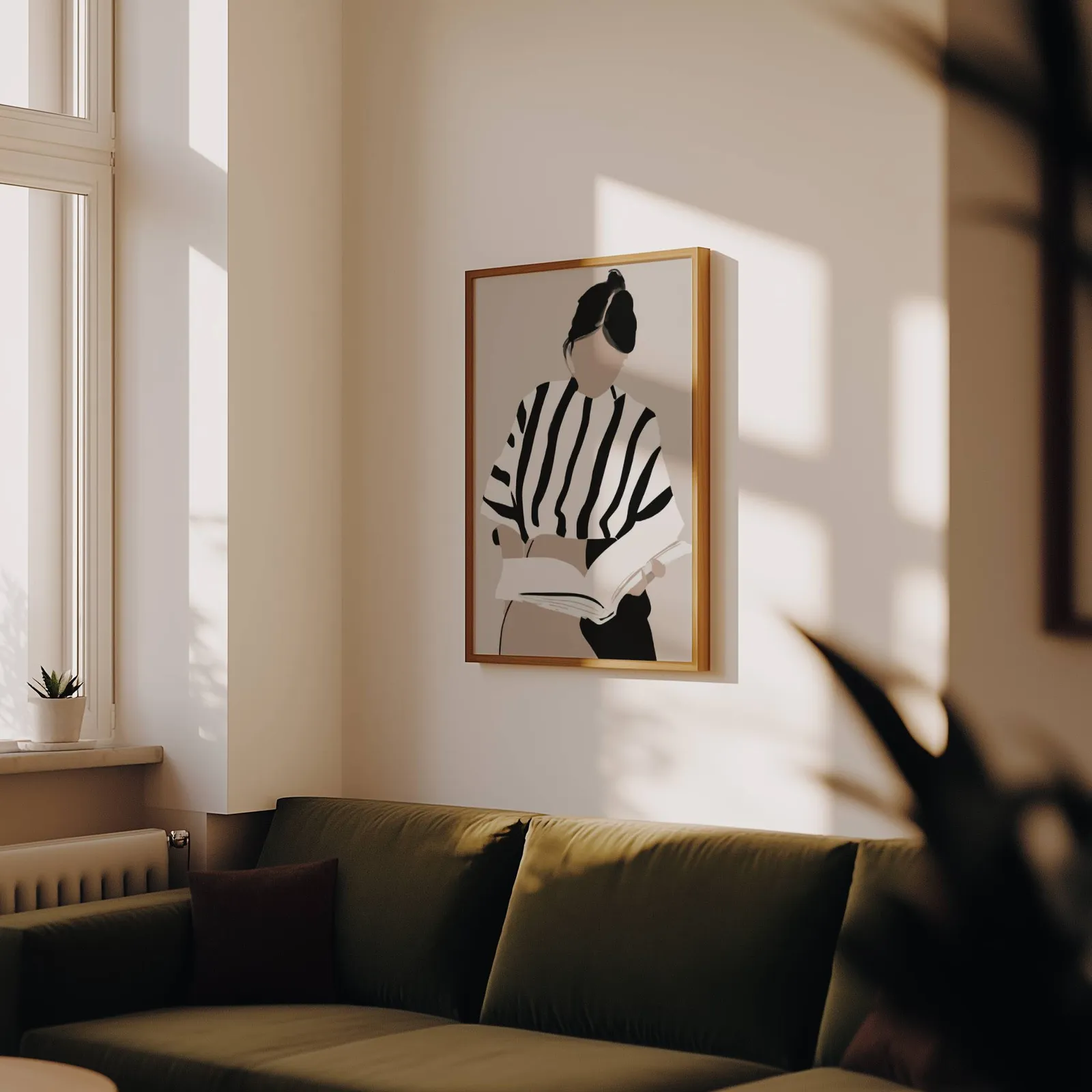 woman reading minimalist wall art, above an olive velvet sofa in raking afternoon light