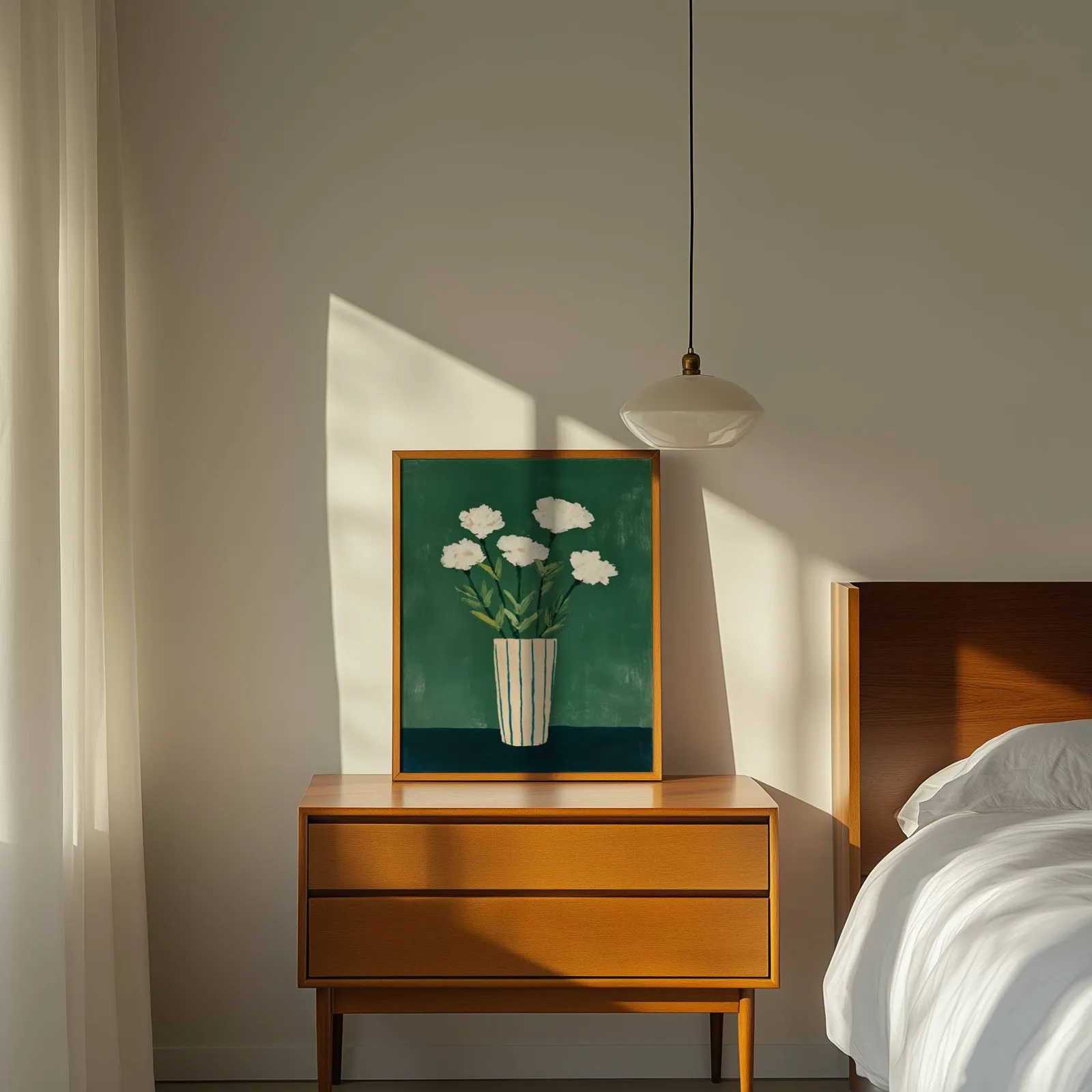 green floral wall art with white flowers in striped vase, propped on a wooden dresser beside a pendant lamp