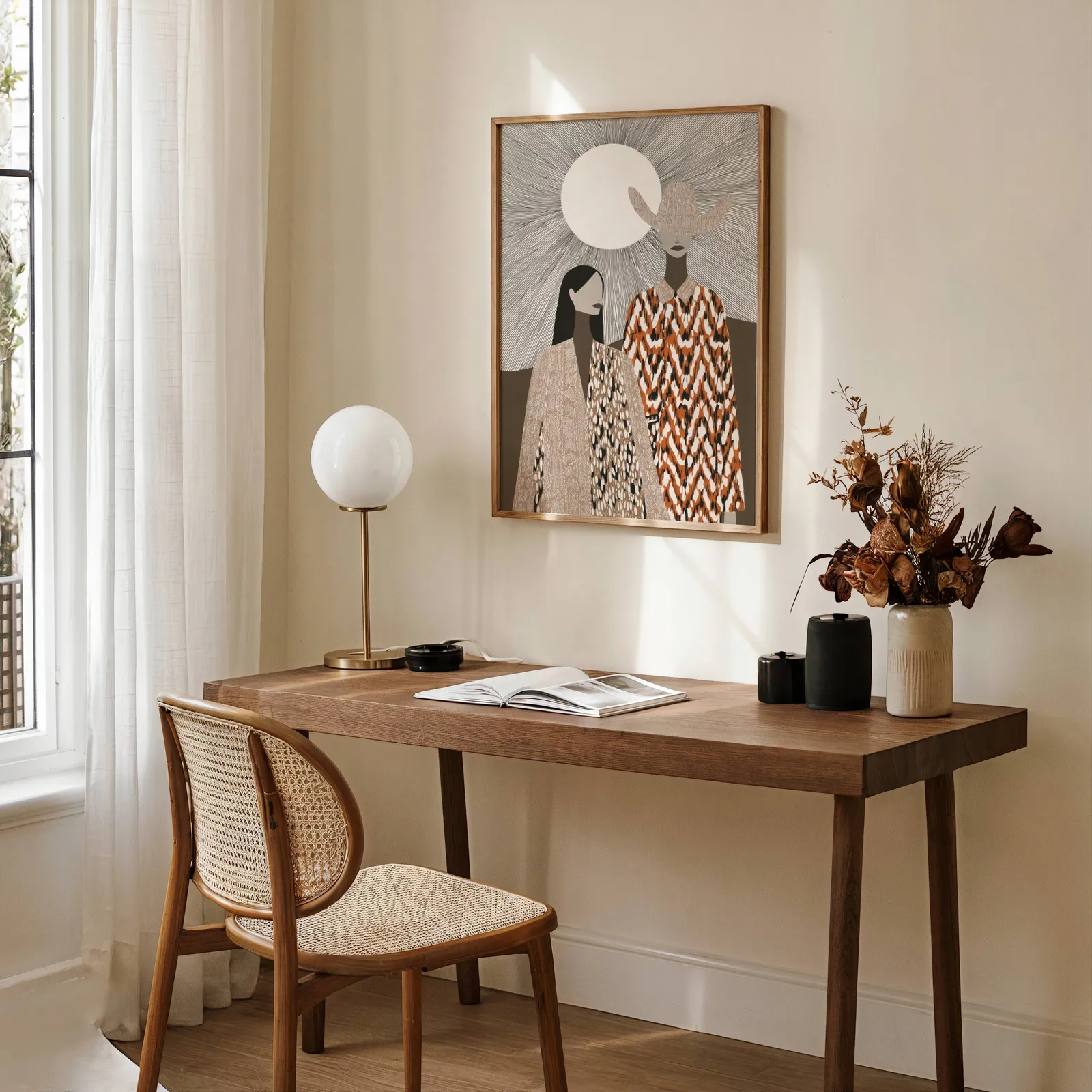 boho western wall art with two women in patterned cloaks, above a wooden desk with a globe lamp and dried flowers