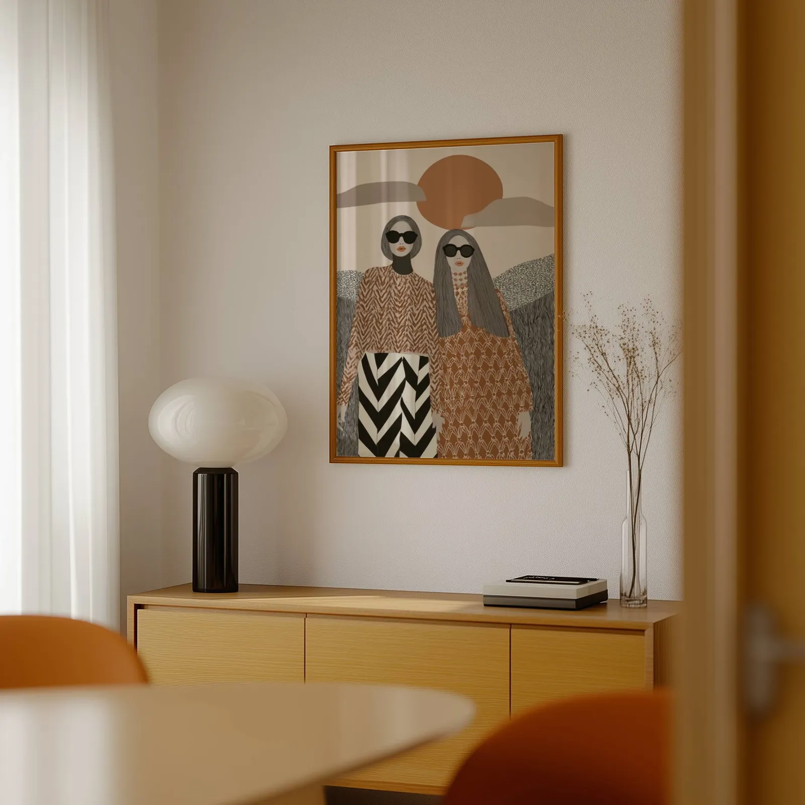 terracotta boho portrait wall art of two women, above a light wood sideboard beside a bulbous black lamp