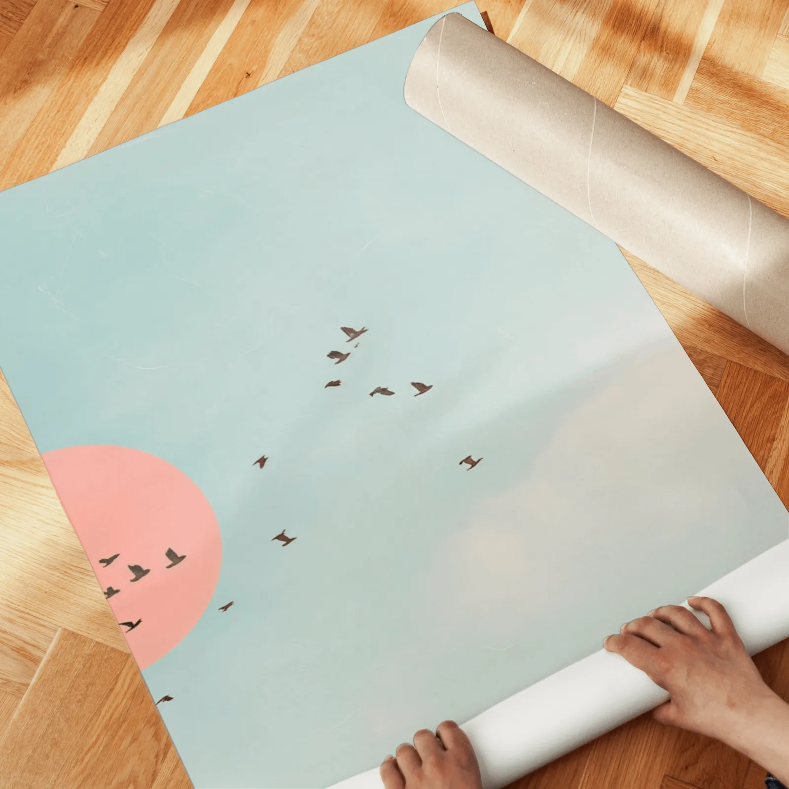 blue and pink bird wall art set of two, unrolled across a herringbone parquet floor by hand