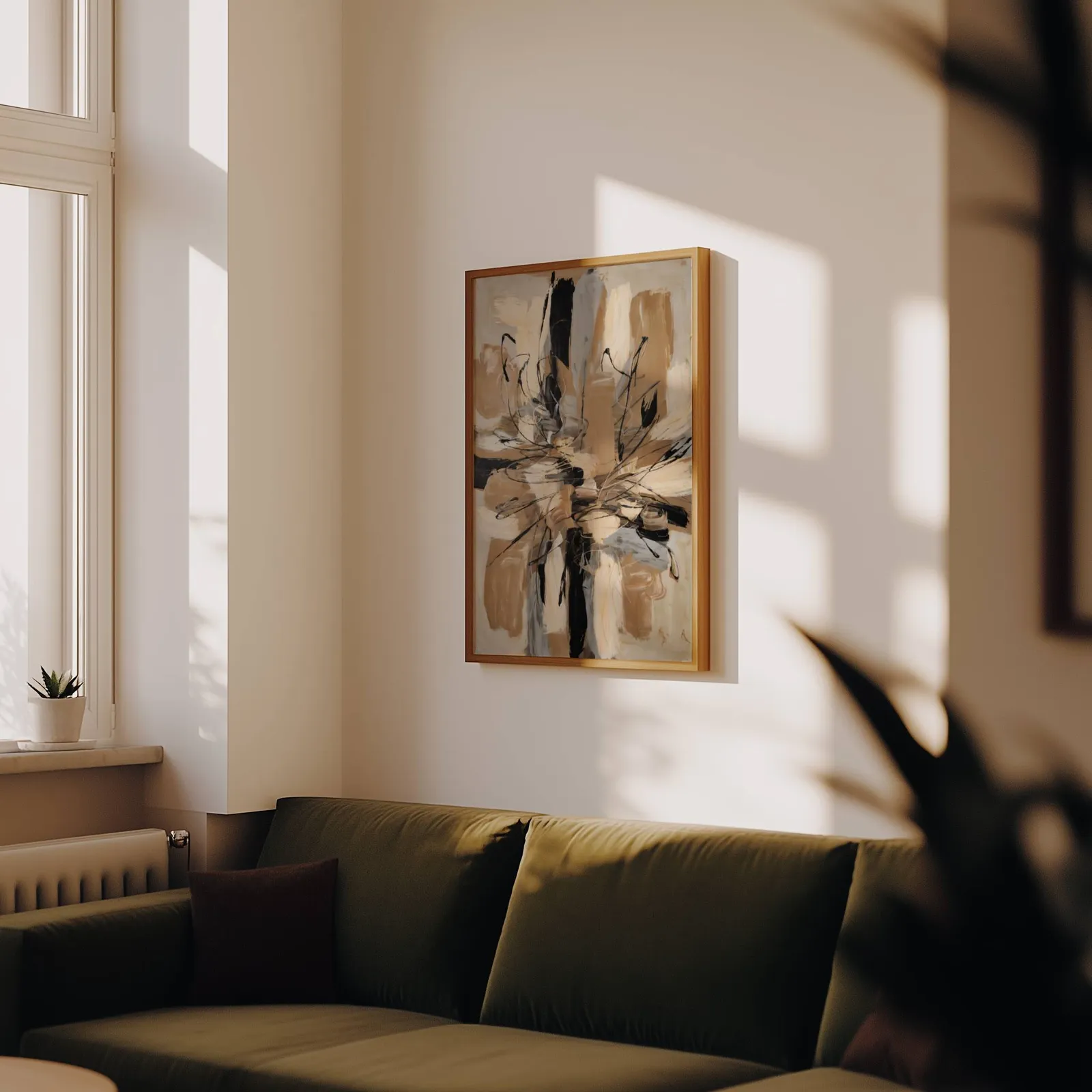 abstract wall art in beige and black, above an olive velvet sofa in raking afternoon light