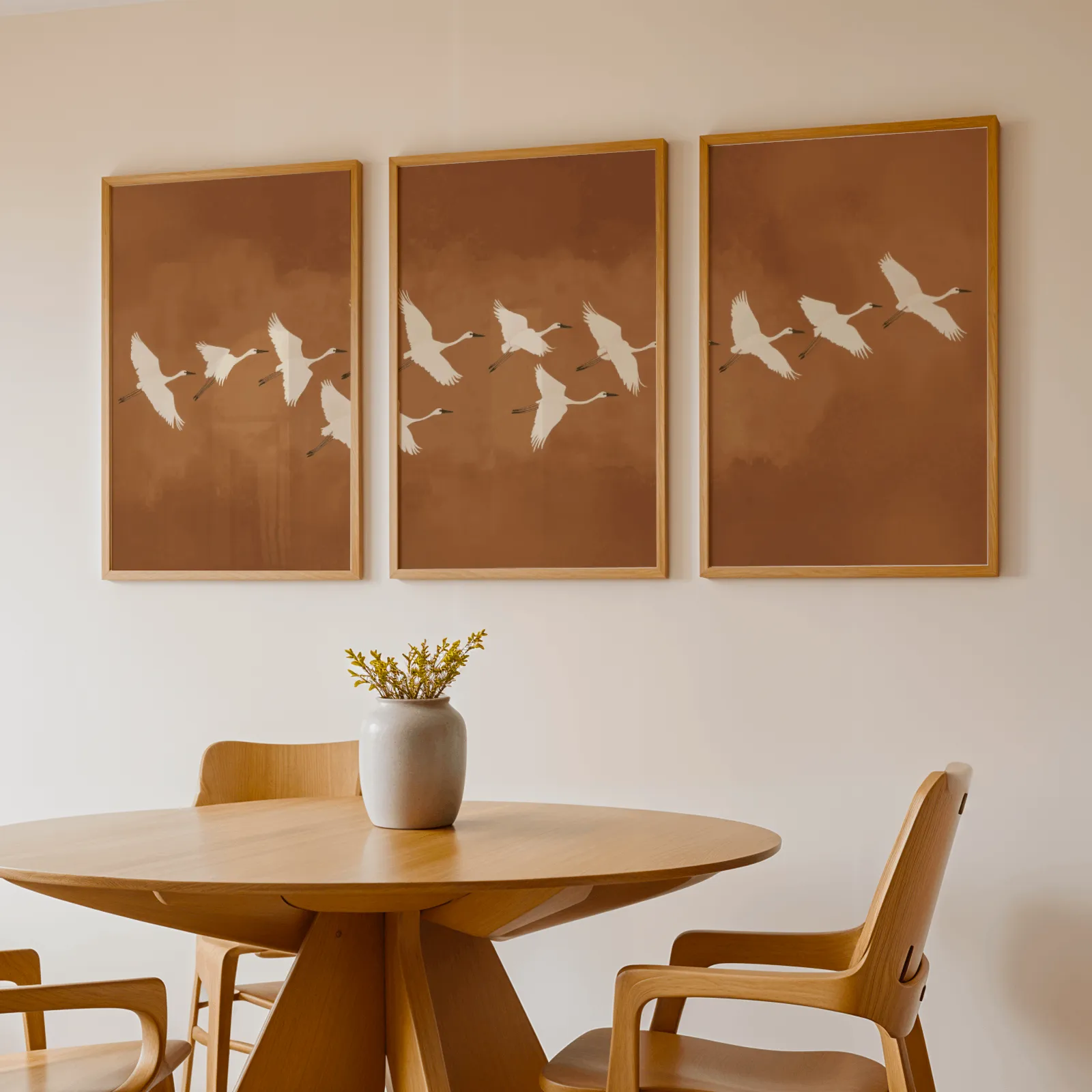 terracotta crane triptych wall art, above a round wooden table with a stoneware vase