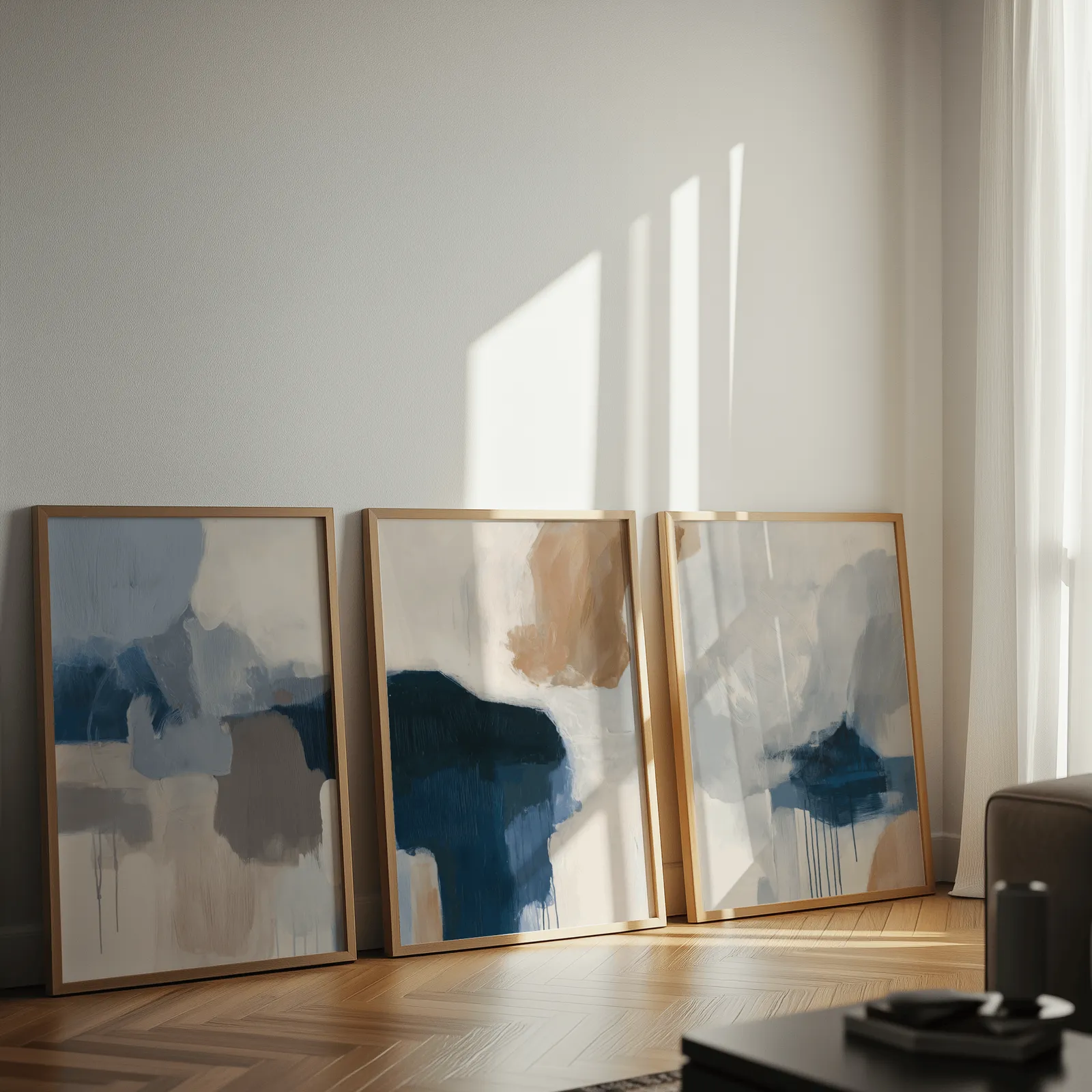 blue beige abstract triptych wall art, leaning against a sunlit wall on herringbone flooring