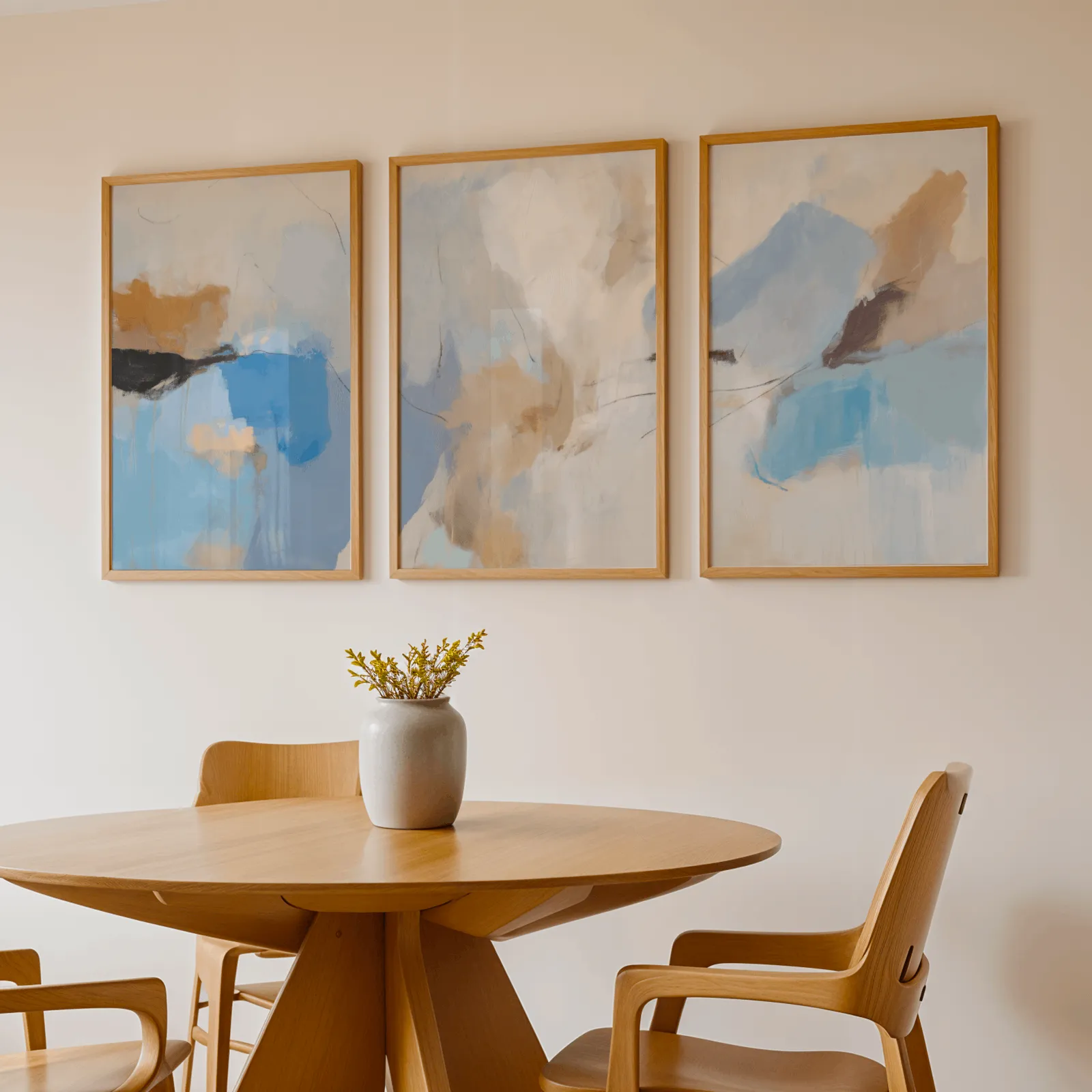 blue and terracotta abstract coastal wall art set of 3, above a round wooden table with a stoneware vase