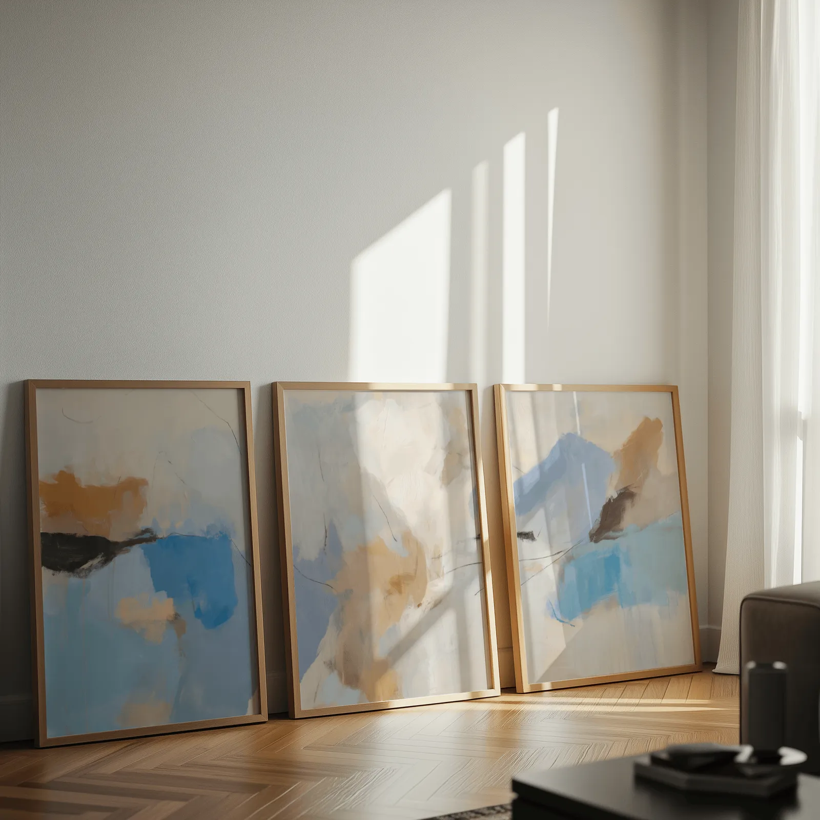 blue and terracotta abstract coastal wall art set of 3, leaning against a sunlit wall on herringbone flooring
