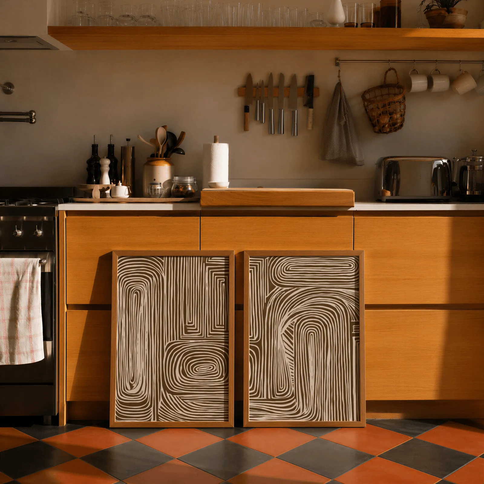 brown abstract line art set of two, leaning against wooden cabinets on terracotta tiled floor