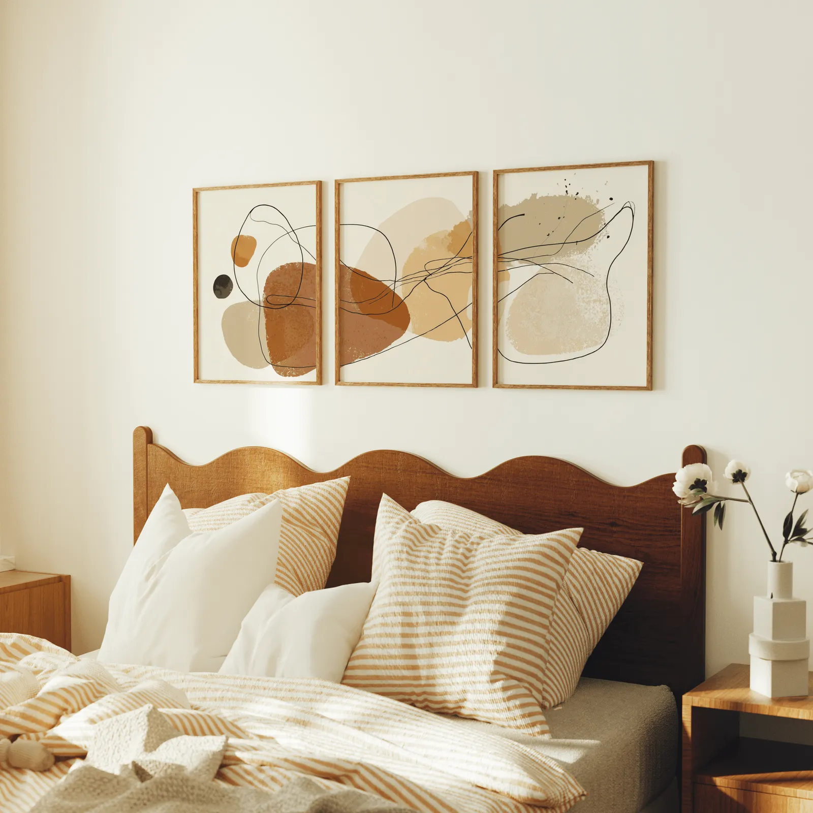 terracotta abstract minimalist wall art set of three, above a scalloped wooden headboard with striped pillows