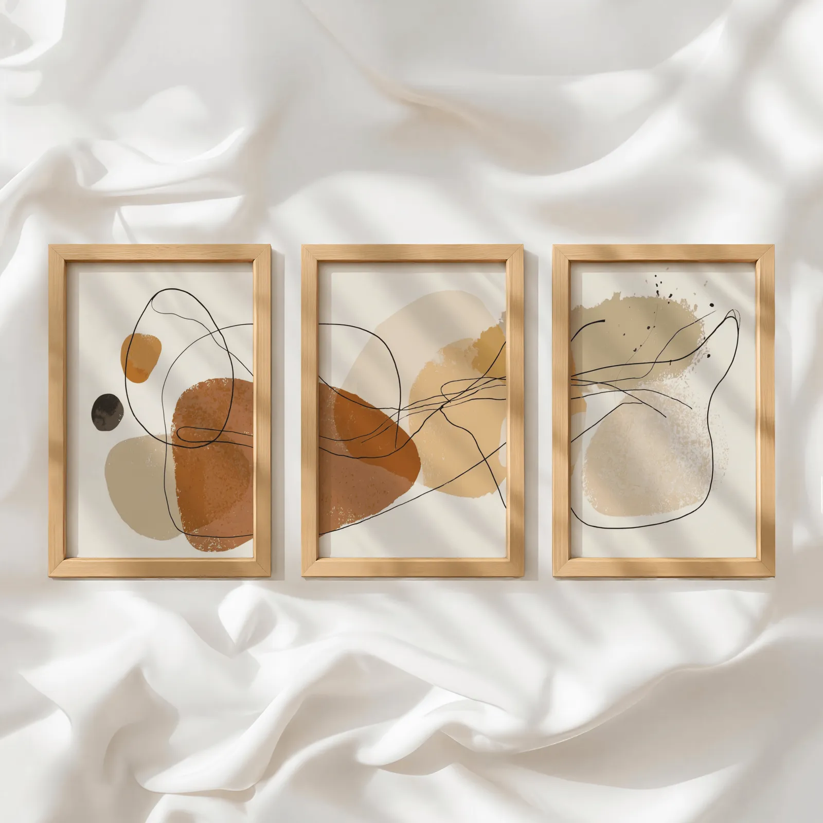 terracotta abstract minimalist wall art set of three, in a row atop rumpled white silky fabric