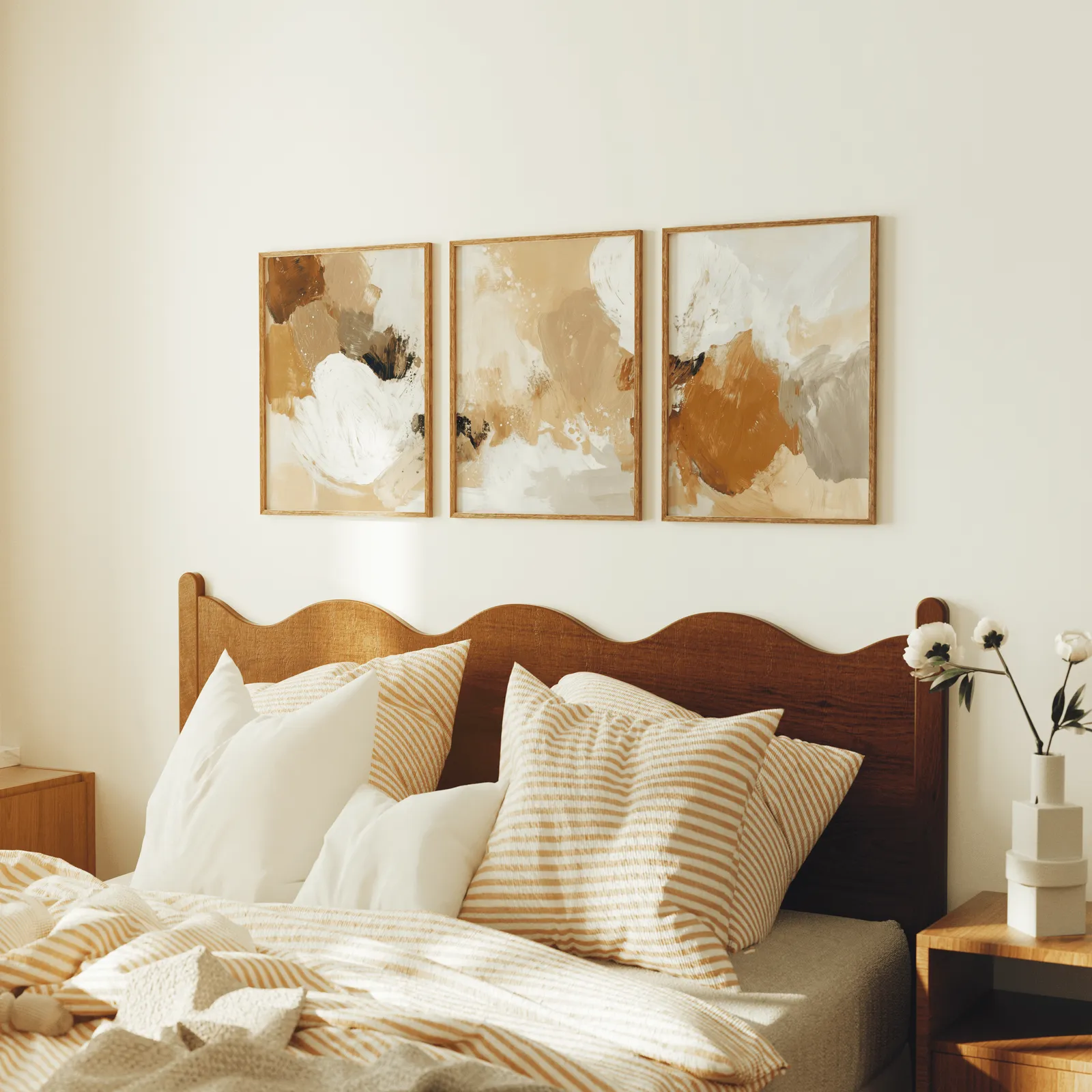 terracotta abstract three piece wall art, above a scalloped wooden headboard with striped pillows