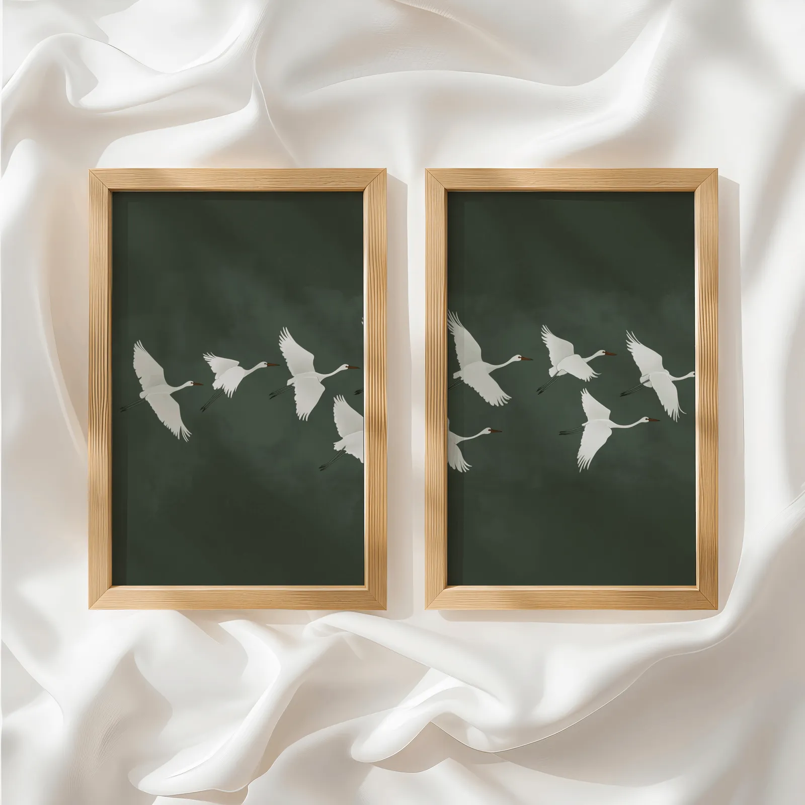 green crane wall art set of two, side by side atop rumpled white silky fabric