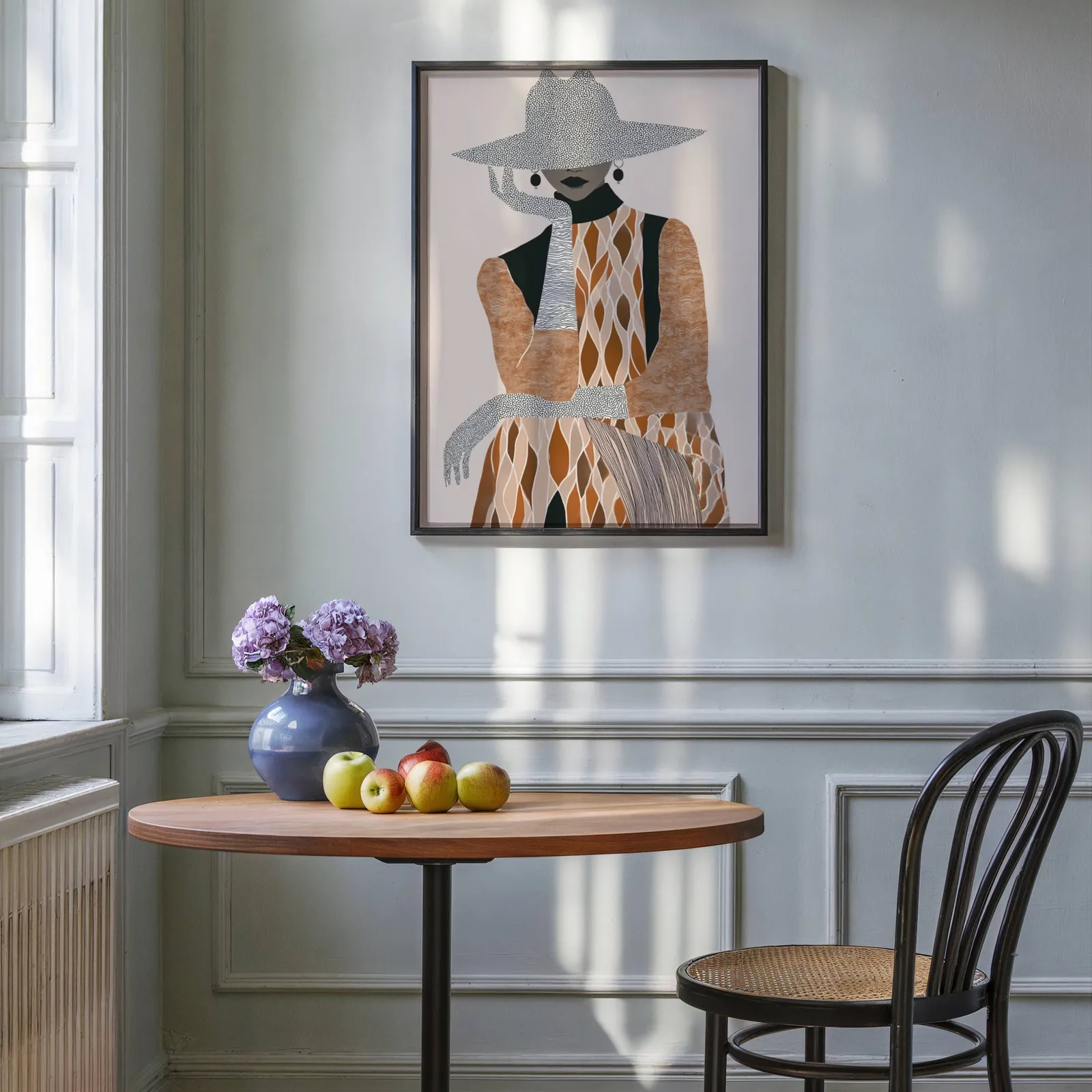 boho woman portrait wall art in brown and cream, above a round wooden table with apples and a blue vase