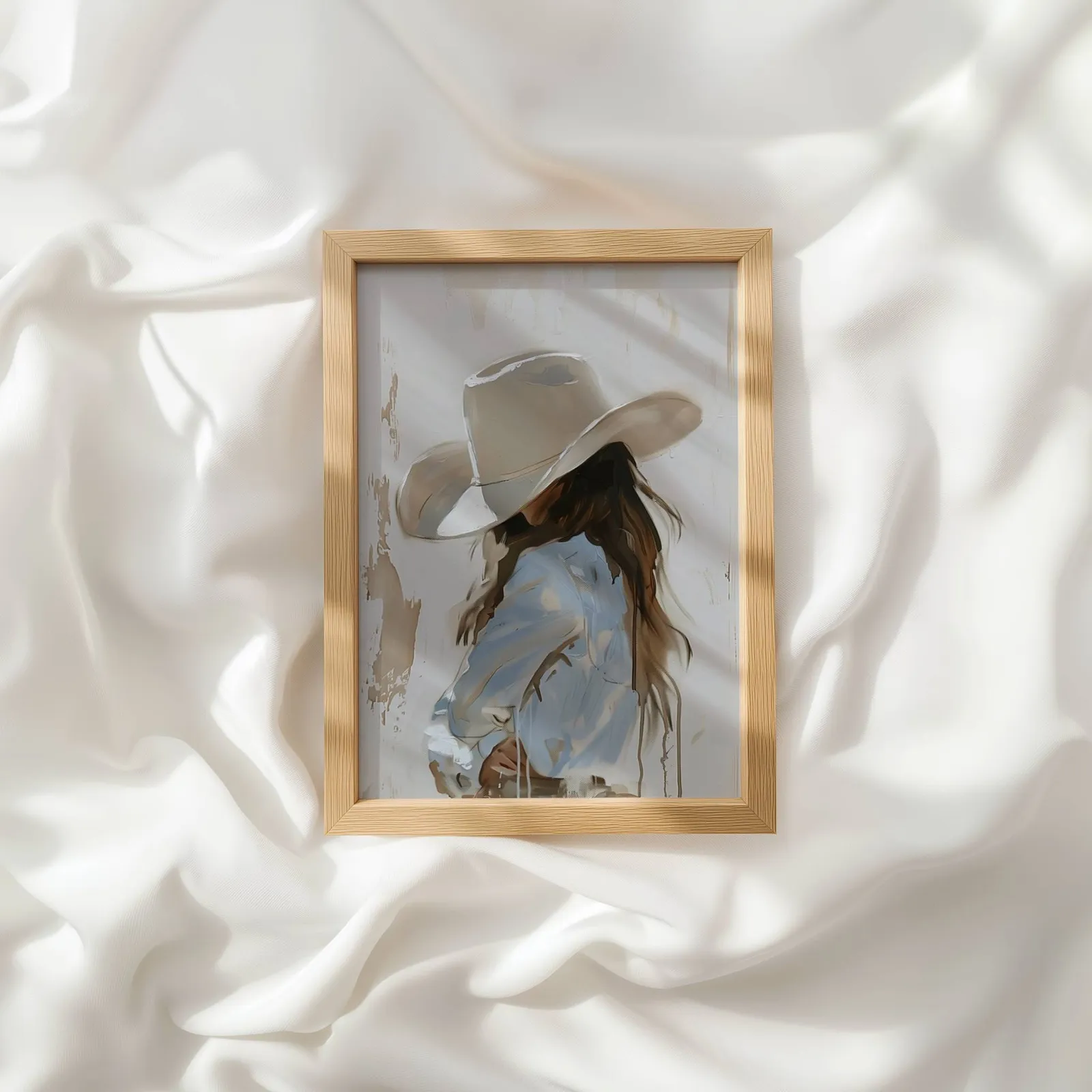 beige western cowgirl portrait wall art, resting atop rumpled white silky fabric