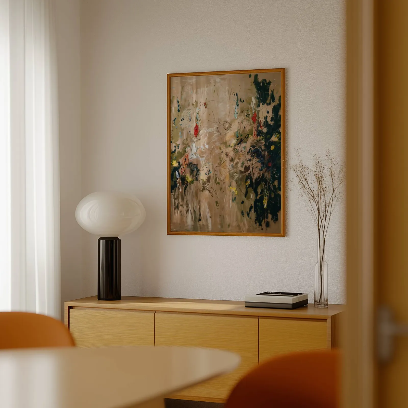 abstract floral wall art in beige and green, above a light wood sideboard beside a bulbous black lamp