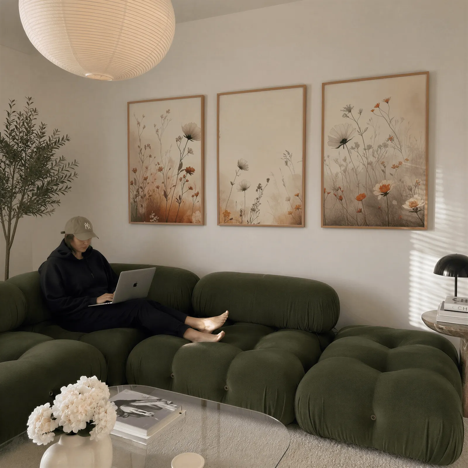 terracotta beige botanical wall art set of 3, above a plush olive velvet sectional beneath a paper lantern light