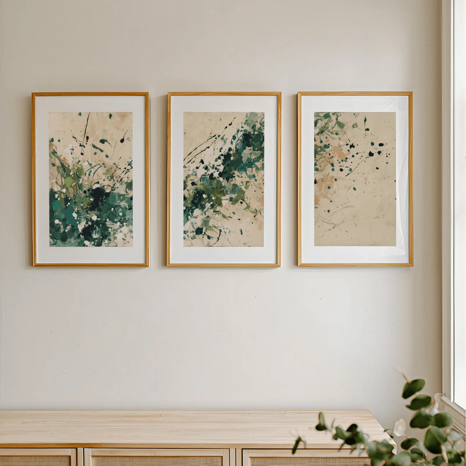 green abstract splatter triptych wall art, in a row above a light wooden sideboard near a window