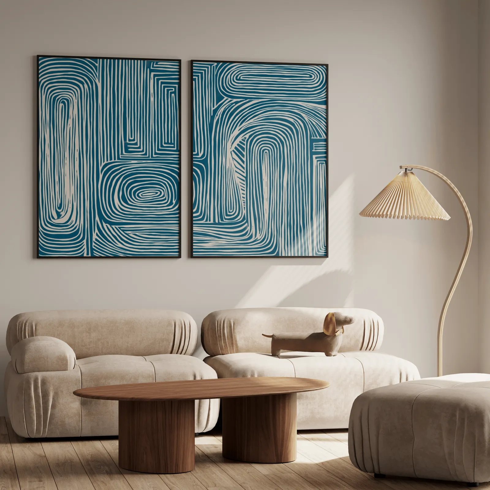 blue abstract line pattern wall art set of 2, above a plush beige sofa with a pleated lamp nearby