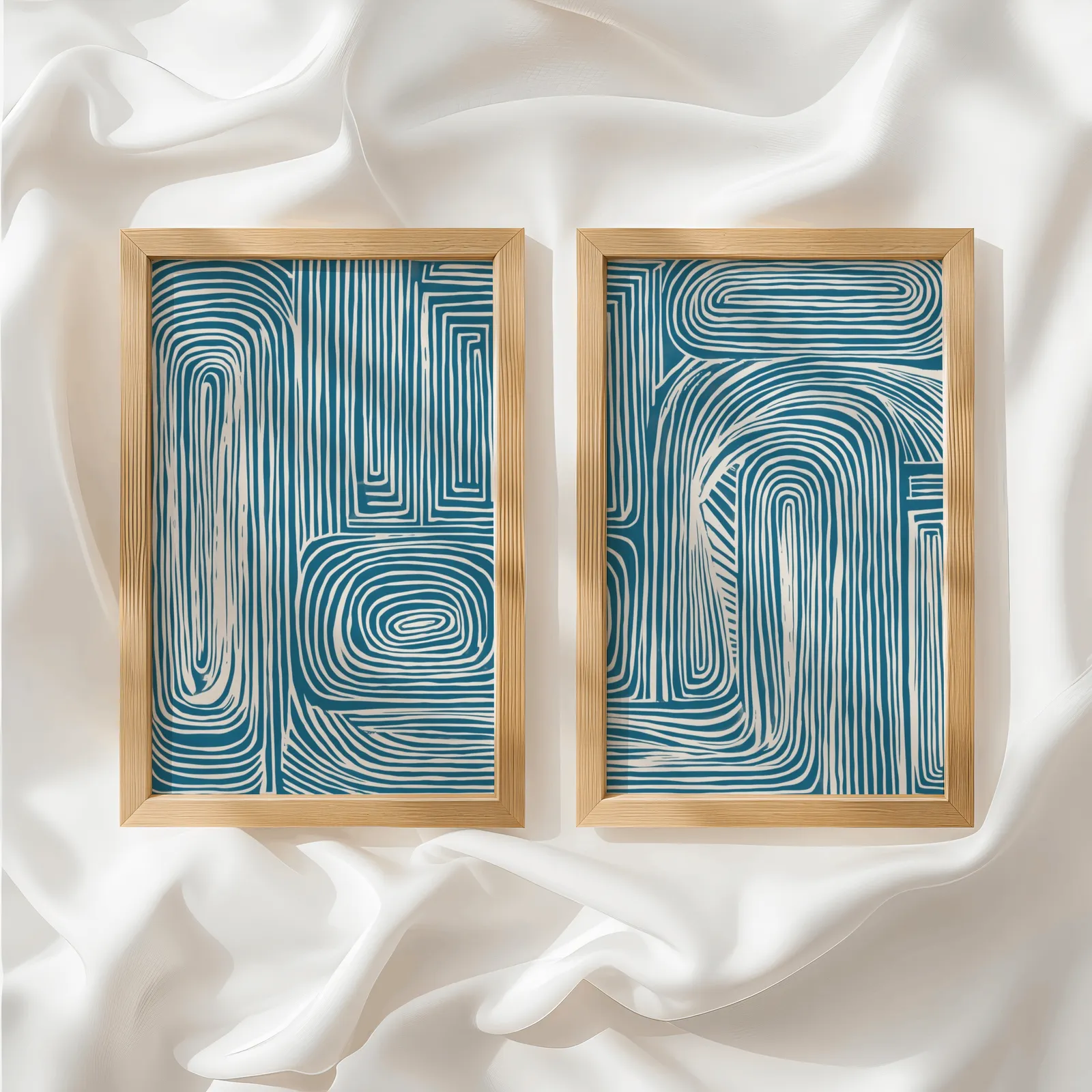 blue abstract line pattern wall art set of 2, side by side atop rumpled white silky fabric
