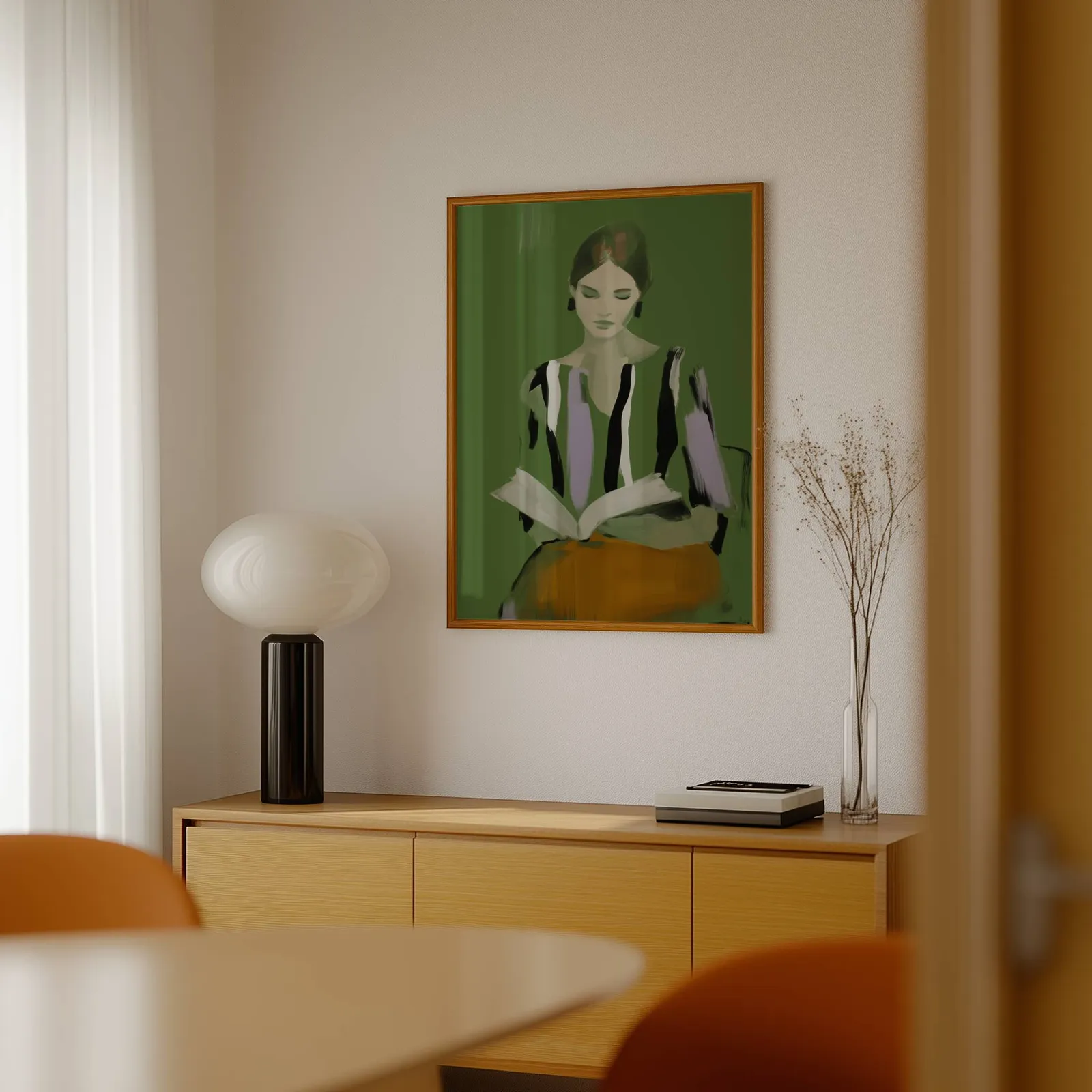 green modern woman reading wall art, above a light wood sideboard beside a bulbous black lamp