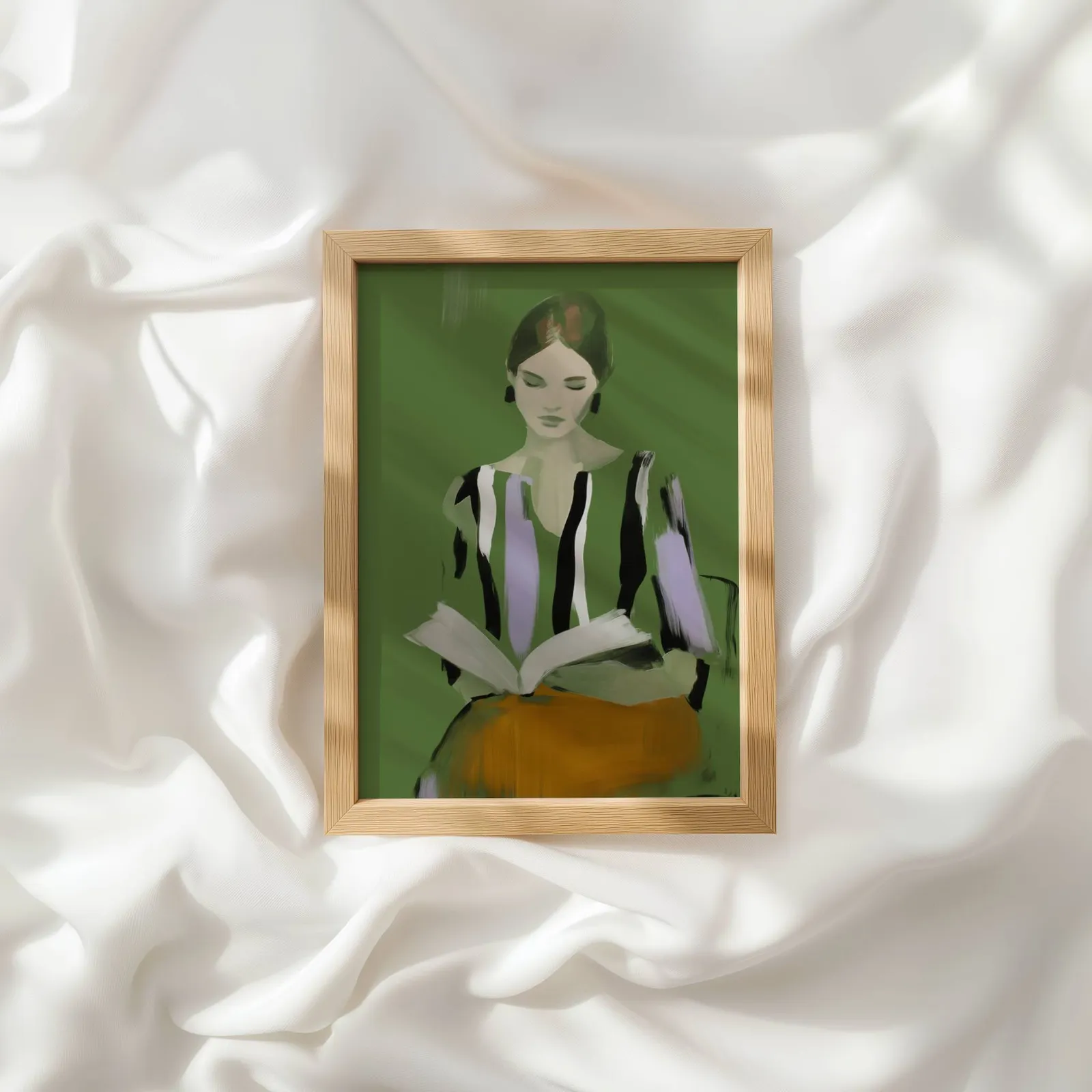 green modern woman reading wall art, resting atop rumpled white silky fabric